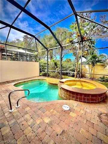 View of swimming pool featuring an in ground hot tub, a patio, and a lanai