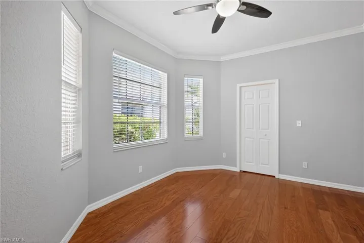 Unfurnished room with dark wood-style flooring, a ceiling fan, and ornamental molding
