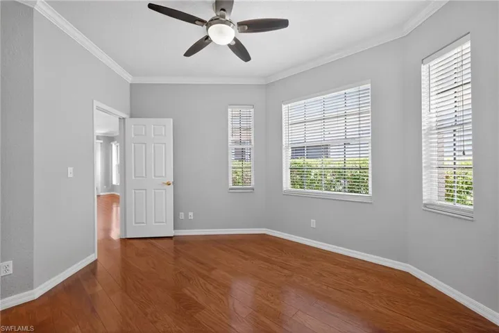 Unfurnished bedroom with ornamental molding, a ceiling fan, and dark wood-style floors
