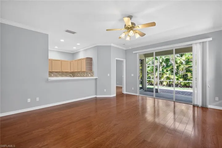 Unfurnished living room featuring recessed lighting, ceiling fan, crown molding, and dark wood-type flooring