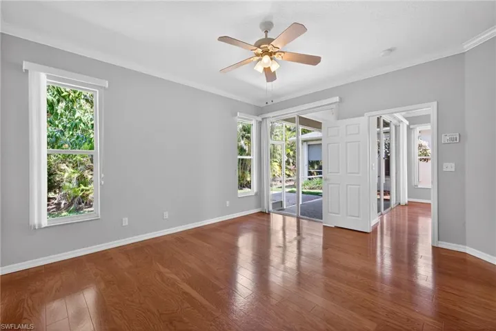 Empty room with ceiling fan, ornamental molding, and dark wood-style floors