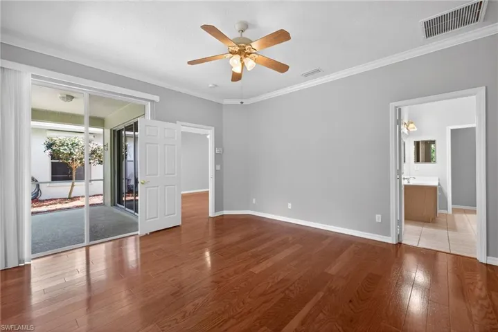 Unfurnished bedroom featuring hardwood / wood-style flooring, access to exterior, crown molding, ceiling fan, and ensuite bathroom