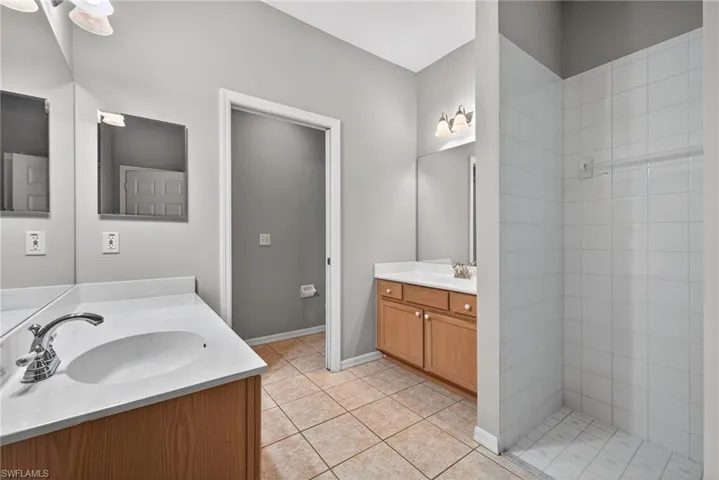 Full bathroom featuring two vanities and light tile patterned floors