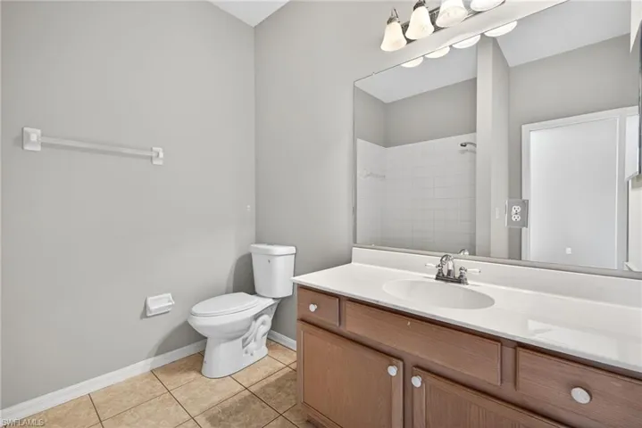 Bathroom with vanity, light tile patterned floors, and a shower