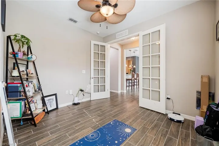 Misc room featuring ceiling fan with notable chandelier, french doors, and dark hardwood / wood-style flooring