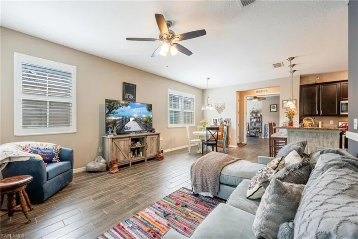 Living room with hardwood / wood-style floors, ceiling fan, and a textured ceiling