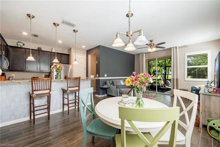 Dining space with dark hardwood / wood-style floors and ceiling fan with notable chandelier