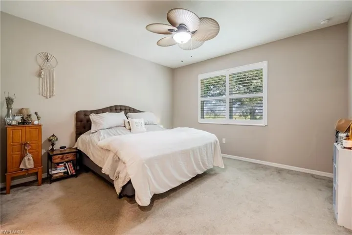 Carpeted bedroom featuring ceiling fan