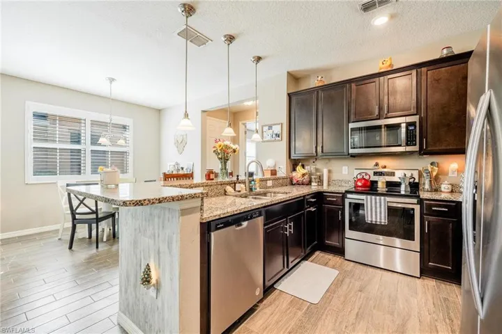 Kitchen with appliances with stainless steel finishes, kitchen peninsula, sink, and pendant lighting
