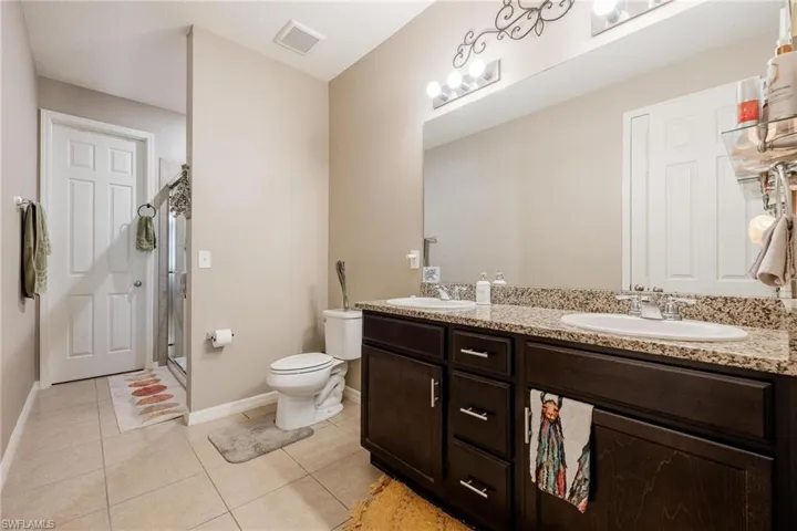Bathroom with tile patterned flooring, vanity, toilet, and walk in shower