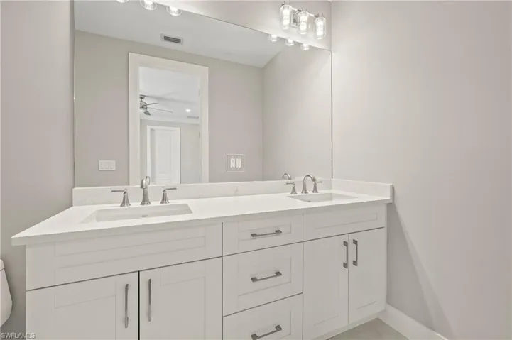 Full bath with double vanity, a sink, ceiling fan, and visible vents