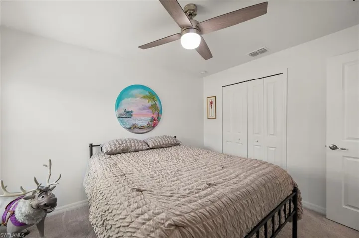 Bedroom with light carpet, a closet, and ceiling fan