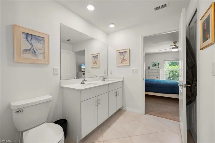 Full bathroom featuring connected bathroom, double vanity, tile patterned flooring, and recessed lighting