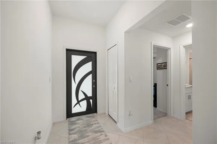 Foyer with light tile patterned flooring and baseboards
