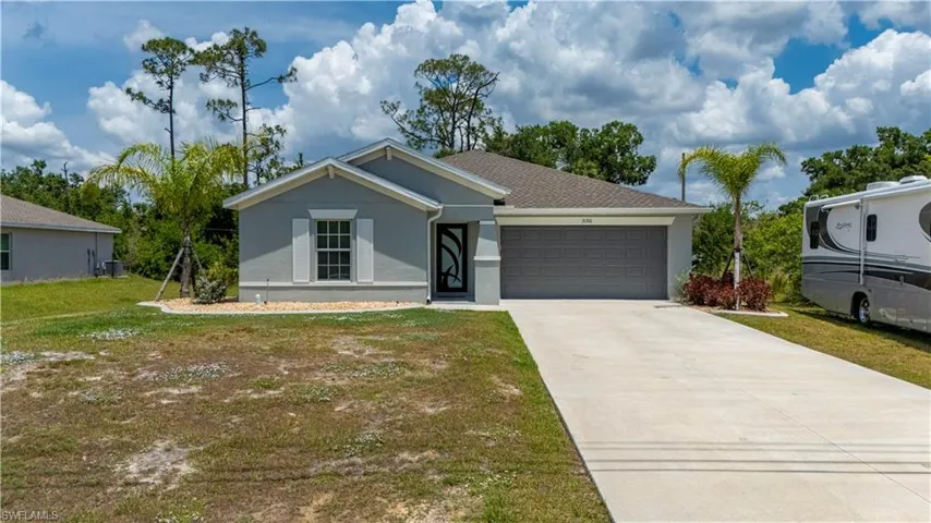 Ranch-style house with an attached garage, concrete driveway, stucco siding, and a front yard