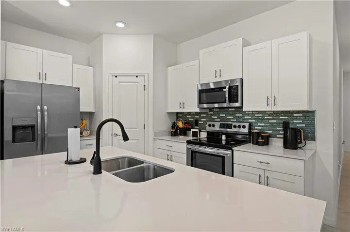 Kitchen featuring appliances with stainless steel finishes, white cabinetry, tasteful backsplash, light countertops, and recessed lighting
