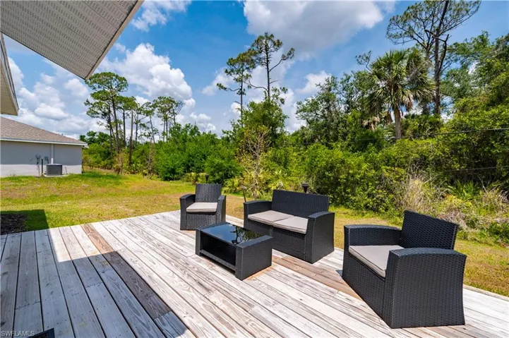 Wooden deck featuring an outdoor hangout area, a yard, and view of scattered trees