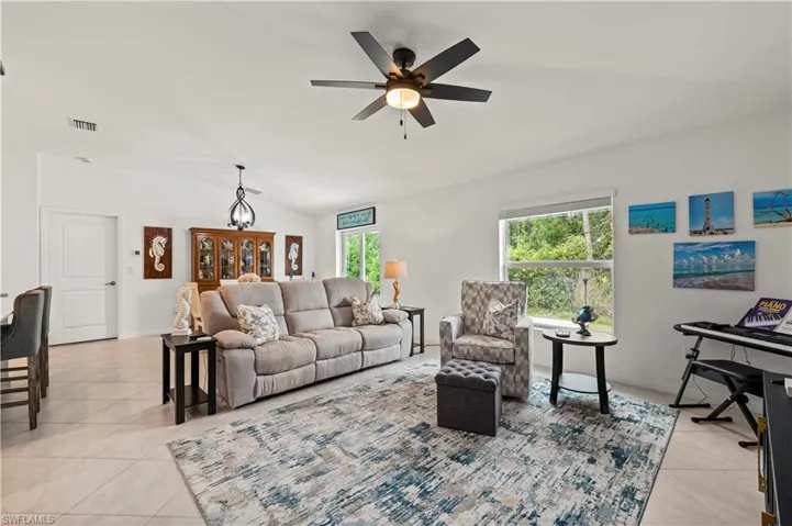 Living room with light tile patterned floors, lofted ceiling, and a ceiling fan