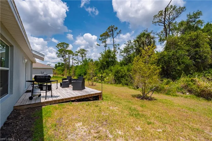 View of green lawn with a deck and an outdoor hangout area