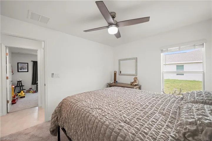 Bedroom featuring light carpet, light tile patterned floors, and a ceiling fan