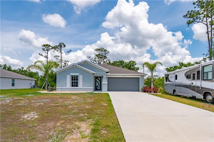 View of front of property featuring an attached garage, stucco siding, driveway, and a front lawn