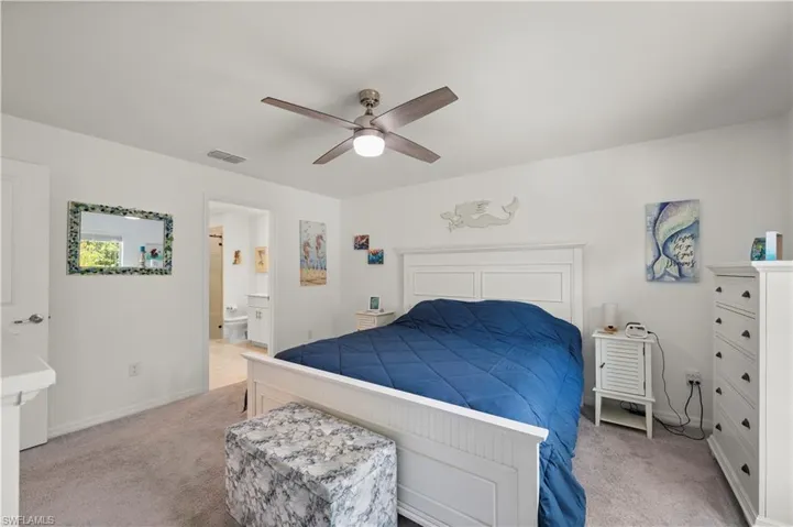 Carpeted bedroom featuring ensuite bath and a ceiling fan