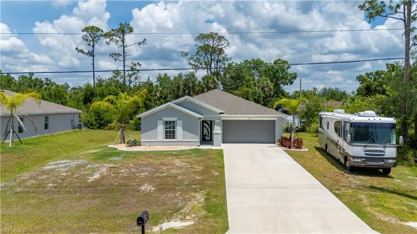 Ranch-style home featuring an attached garage, a front yard, driveway, and stucco siding