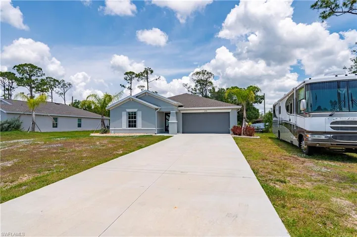 View of front of home featuring a garage, a front lawn, concrete driveway, and stucco siding