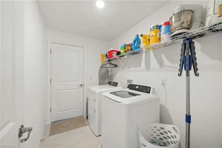 Laundry area with independent washer and dryer and light tile patterned floors