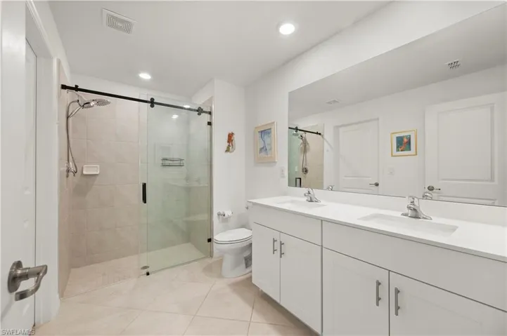 Bathroom featuring a stall shower, double vanity, tile patterned flooring, and recessed lighting