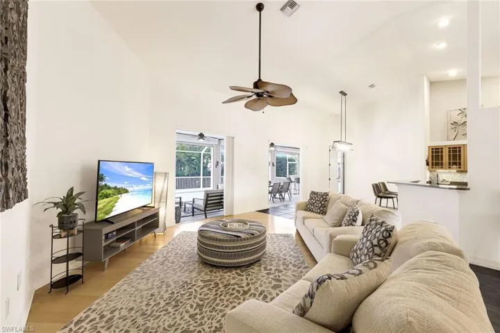 Living room with light wood-look flooring, high vaulted ceiling, and ceiling fan
