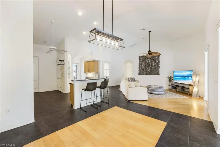 Dining area featuring dark tile flooring with wood-look inlay, high vaulted ceiling, and light fixture