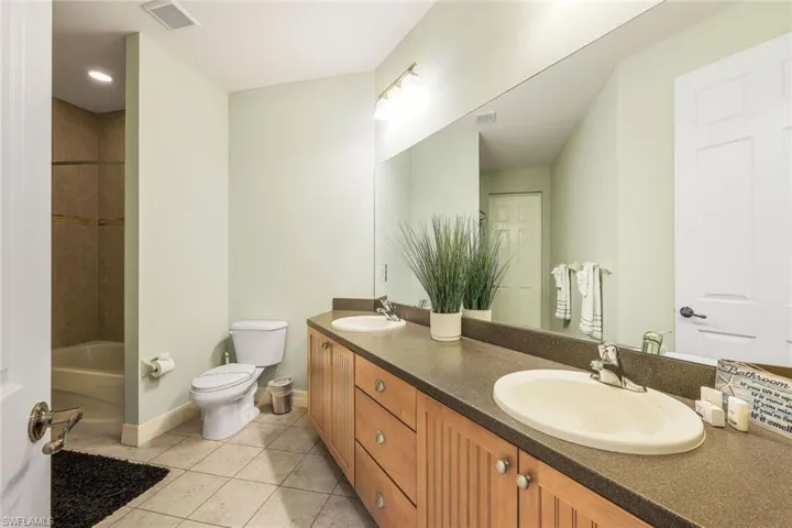 Full bathroom with vanity, toilet, tile patterned floors, and tiled shower / bath