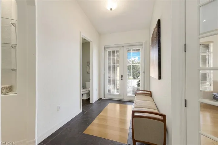 Doorway to outside with french doors, lofted ceiling, and dark tile patterned flooring