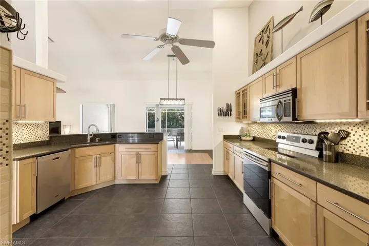 Kitchen with high vaulted ceiling, stainless steel appliances, sink, and light brown cabinets