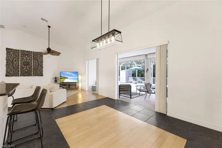 Dining area featuring dark tile flooring with wood-look inlay, high vaulted ceiling, and light fixture