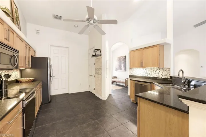 Kitchen with appliances with stainless steel finishes, sink, backsplash, kitchen peninsula, and ceiling fan