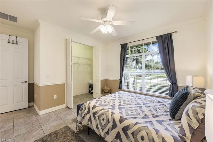 Tiled bedroom featuring ornamental molding, a spacious closet, and ceiling fan