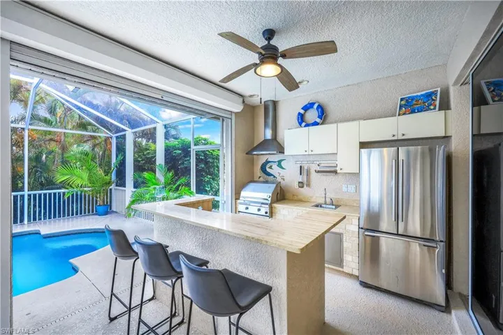Kitchen featuring a breakfast bar area, kitchen peninsula, white cabinets, and stainless steel refrigerator