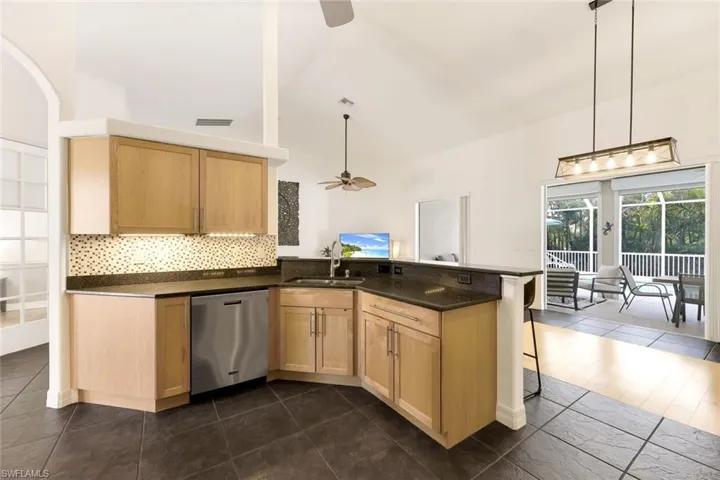 Kitchen with a breakfast bar area, kitchen peninsula, sink, stainless steel dishwasher, and ceiling fan