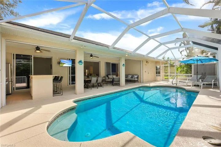 View of swimming pool featuring a patio, ceiling fan, glass enclosure, and an outdoor hangout area