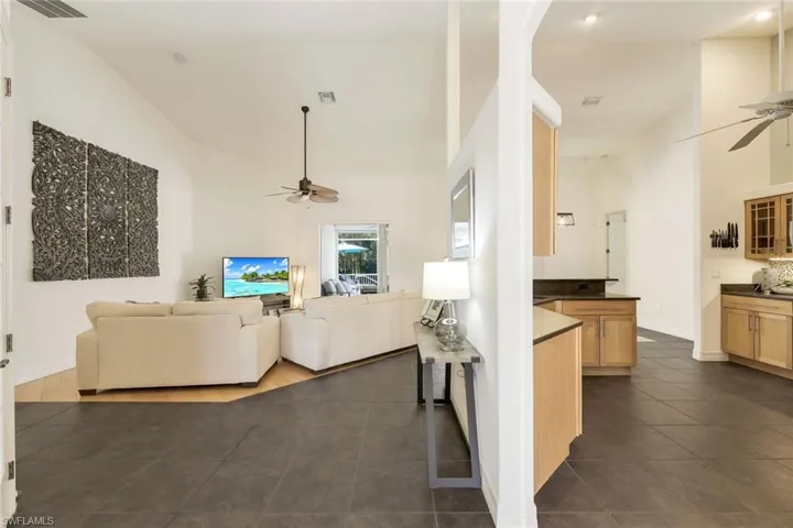 Living room with dark tile patterned flooring, ceiling fan, and high vaulted ceiling