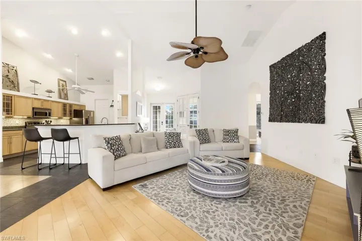 Living room featuring high vaulted ceiling, light wood-look flooring, and ceiling fan