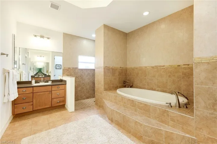 Bathroom with vanity, tile patterned floors, independent shower and bath, and tile walls