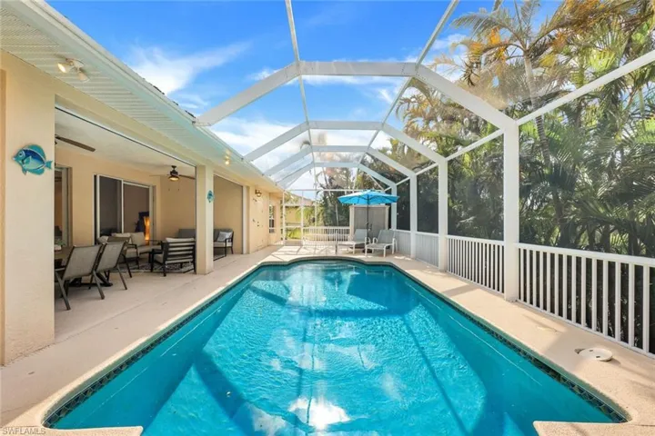 View of pool featuring a patio, ceiling fan, and glass enclosure
