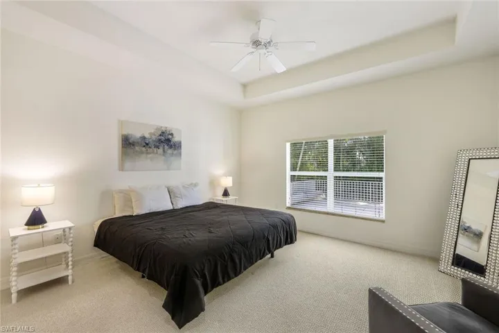 Carpeted bedroom featuring a tray ceiling and ceiling fan