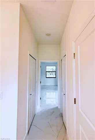 Hall featuring light marble finish floors and a textured ceiling
