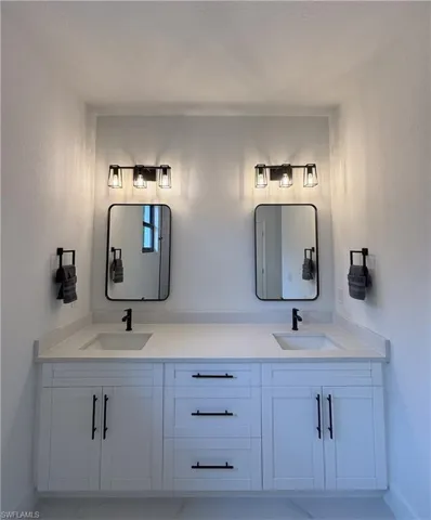 Full bathroom featuring double vanity and a textured wall