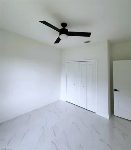 Unfurnished bedroom featuring a ceiling fan, a closet, and light marble finish flooring