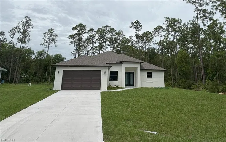 Prairie-style home featuring a front yard, concrete driveway, a garage, a shingled roof, and stucco siding